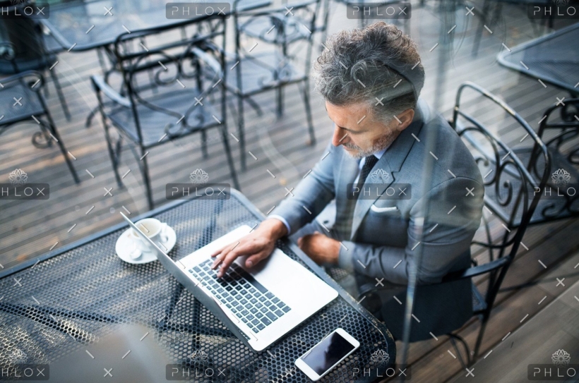 demo-attachment-24-mature-businessman-with-laptop-outside-a-cafe-PXAVBAC